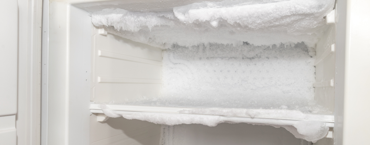 A freezer with excessive ice and frost build-up on the shelves and walls, showing the need for defrosting or maintenance.