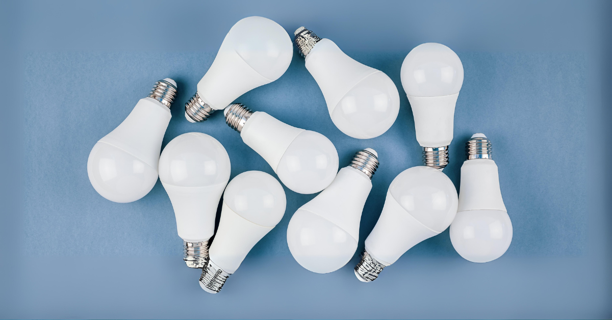 A collection of white LED light bulbs with metallic bases scattered on a light blue surface, representing energy-efficient lighting solutions