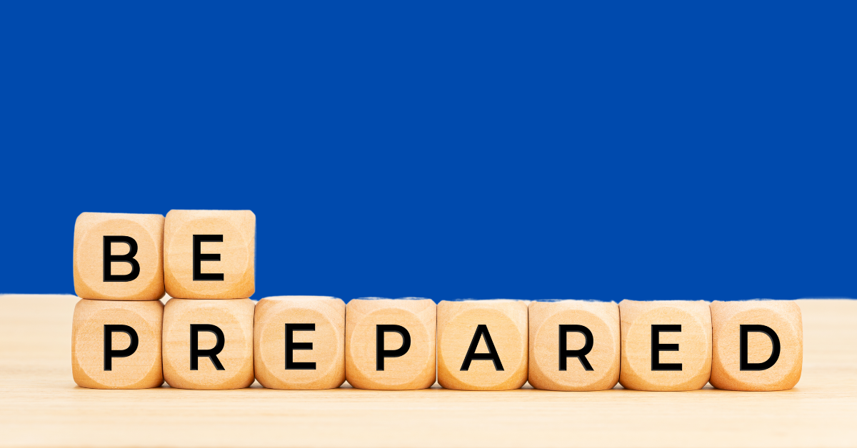 Wooden blocks arranged to spell 'BE PREPARED' on a light wooden surface, set against a solid blue background